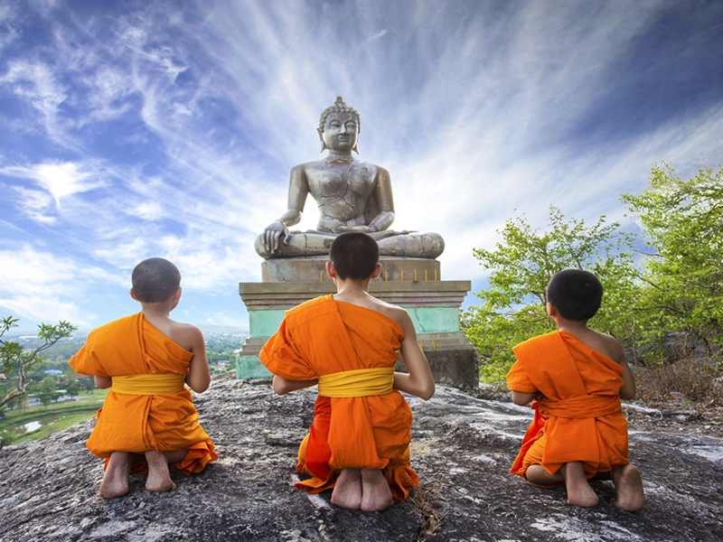 Buddha heykeli önünde diz çökmüş rahipler