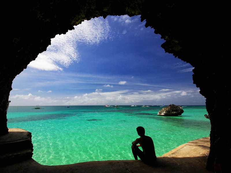 Mağara girişinde denizi izleyen turist